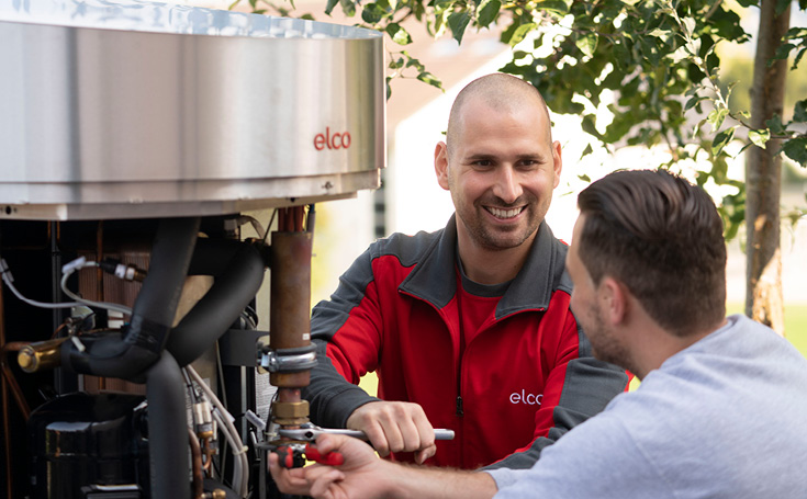 Twee servicetechnici werken aan een verwarmings- of warmtepompinstallatie buiten.
